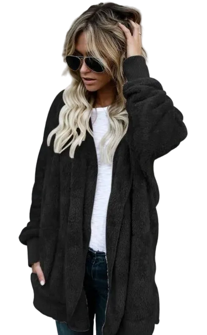 Woman wearing a black cardigan over a white top with sunglasses on a gray background