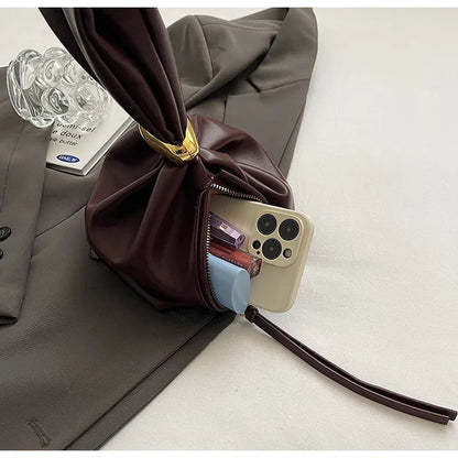 Brown leather pouch with gold clasp on a gray surface