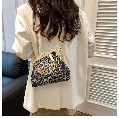 Person wearing a Carauana_UNIU_Leopard_Clutch with gold chain detail