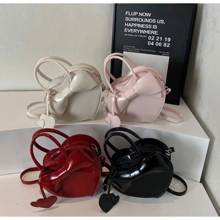 Four small handbags in red, black, pink, and white on a white surface.